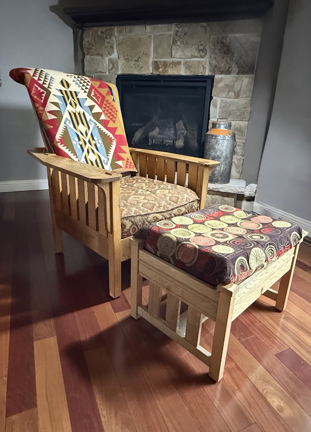 Mission-style oak chair with ottoman beside stone fireplace