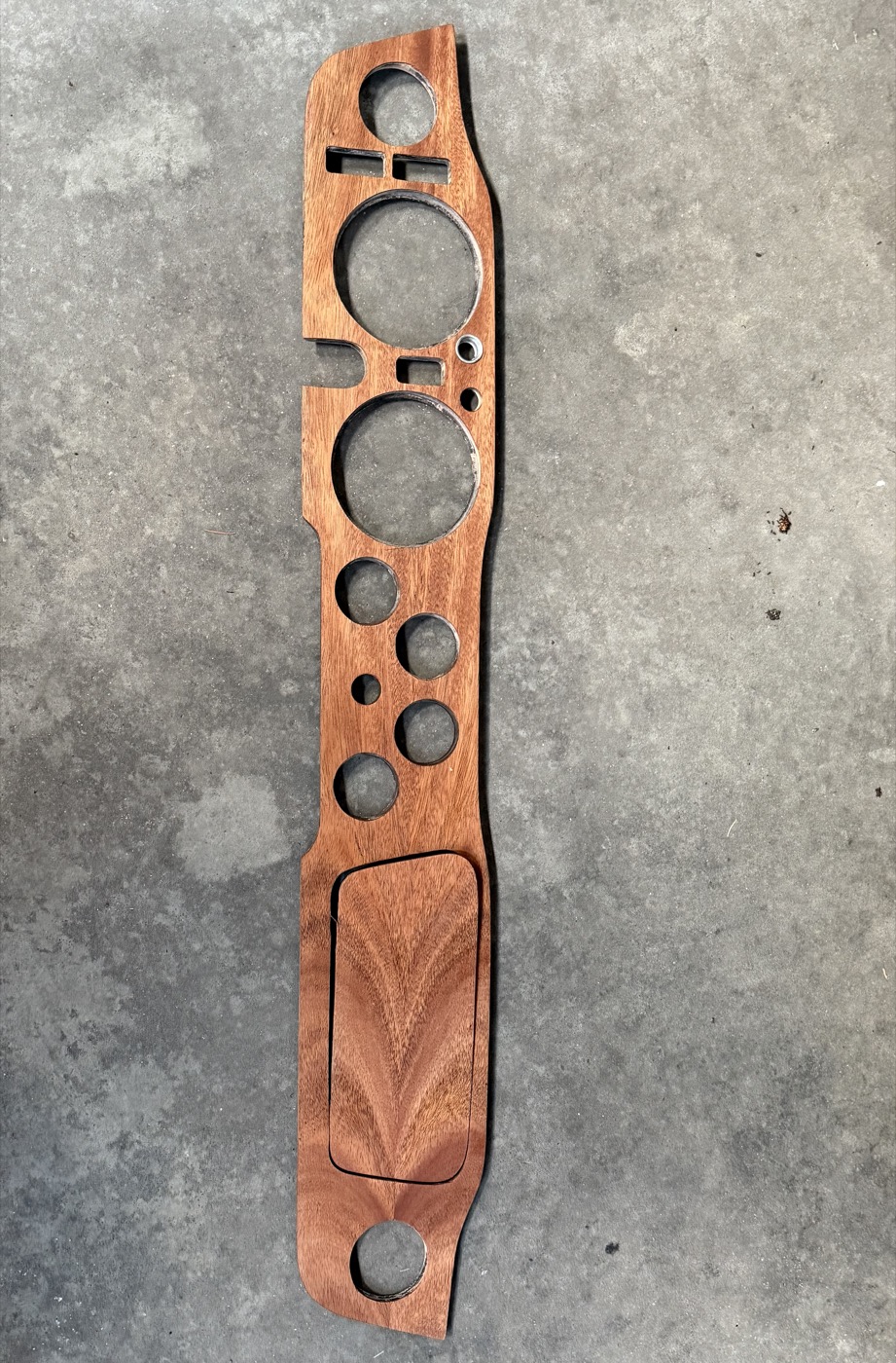 Custom mahogany car dashboard panel with routed gauge and control cutouts