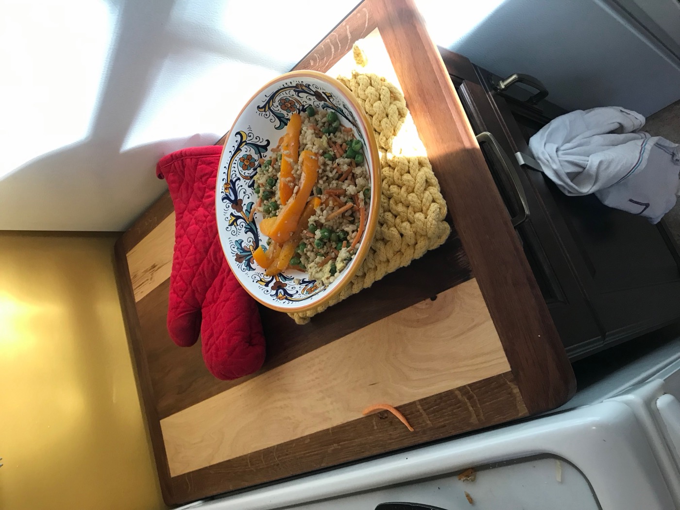 Maple and walnut stove-cover cutting board in a camper kitchen