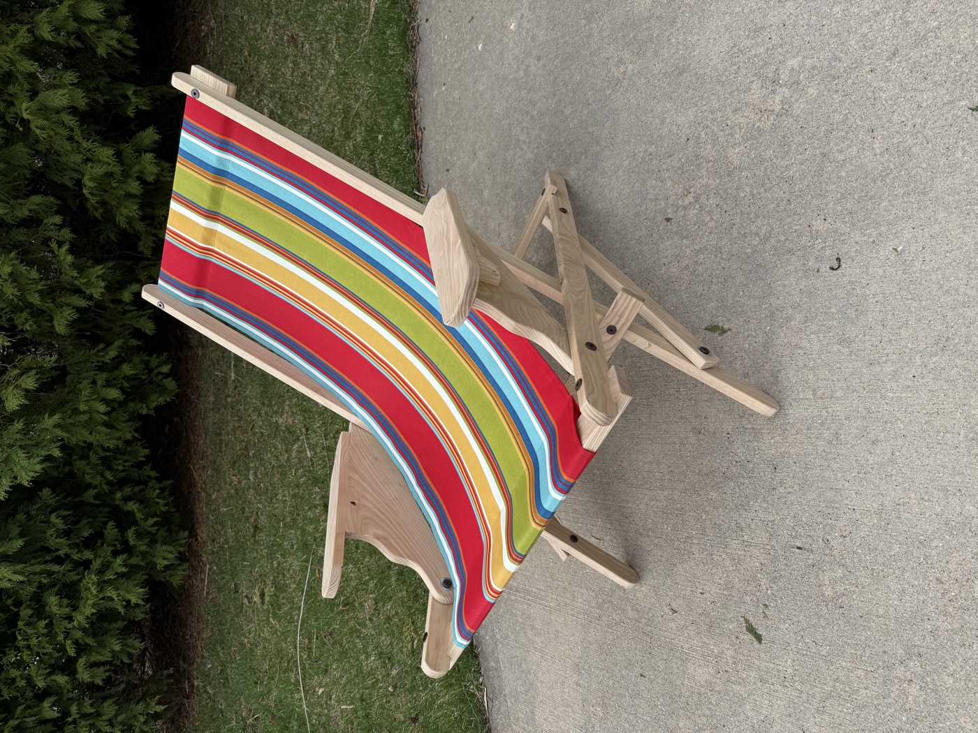 Handcrafted folding sling chair with colorful striped fabric, set up outdoors